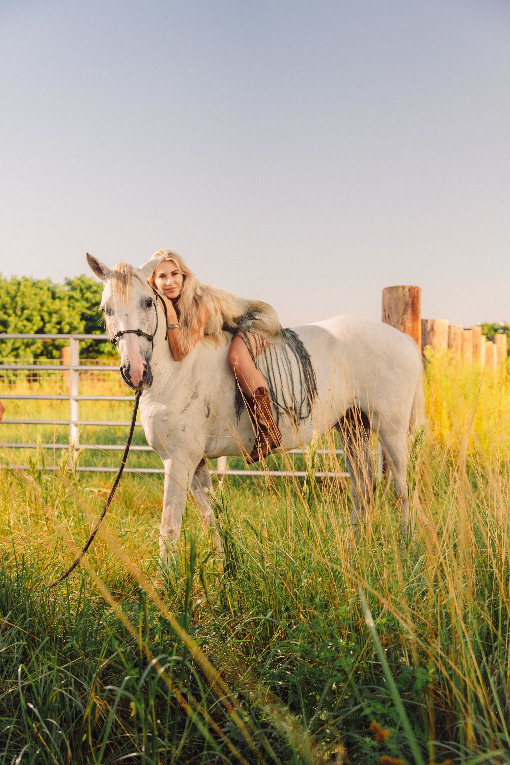 Woman leaning on a white horse in golden light
