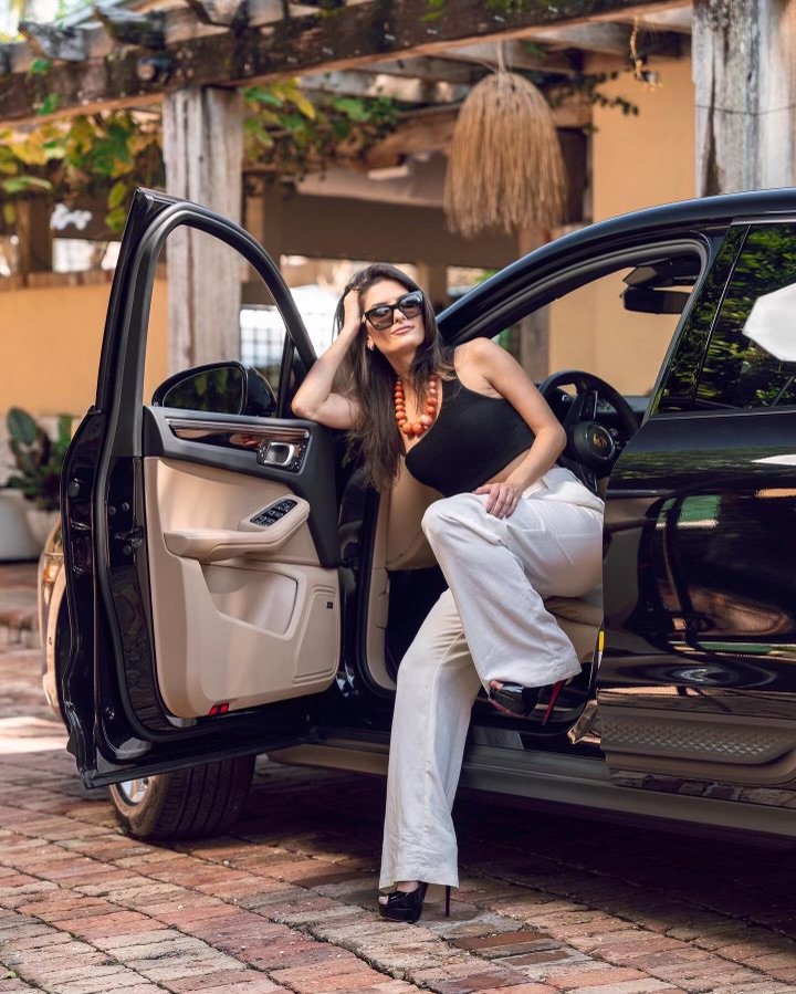 Woman posing in the door of a Porsche